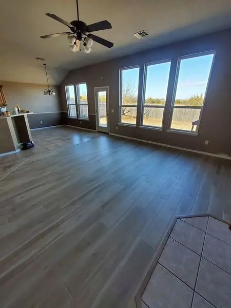 Open living room with wood-look flooring and large windows, finished by TLC Renovation