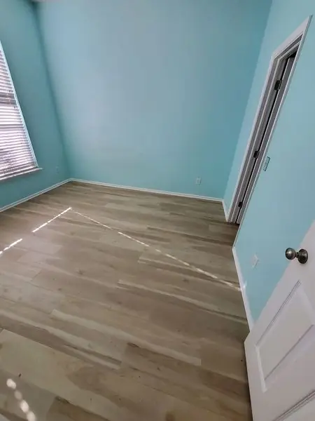 Teal-painted bedroom with new wood-look flooring