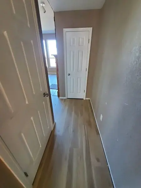 Hallway with wood-look flooring and white doors