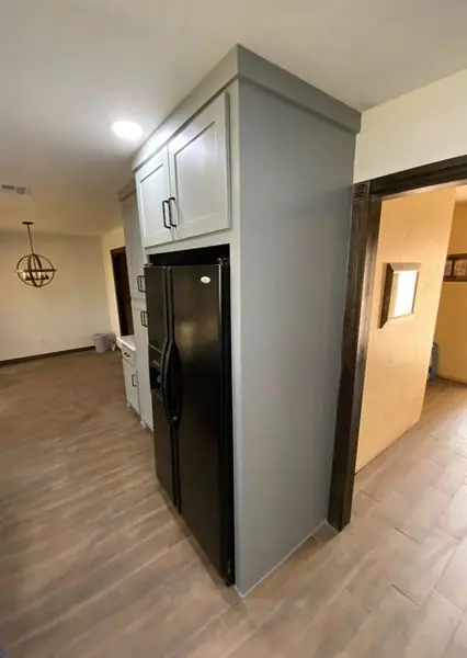 Kitchen with grey cabinetry built around an integrated black refrigerator